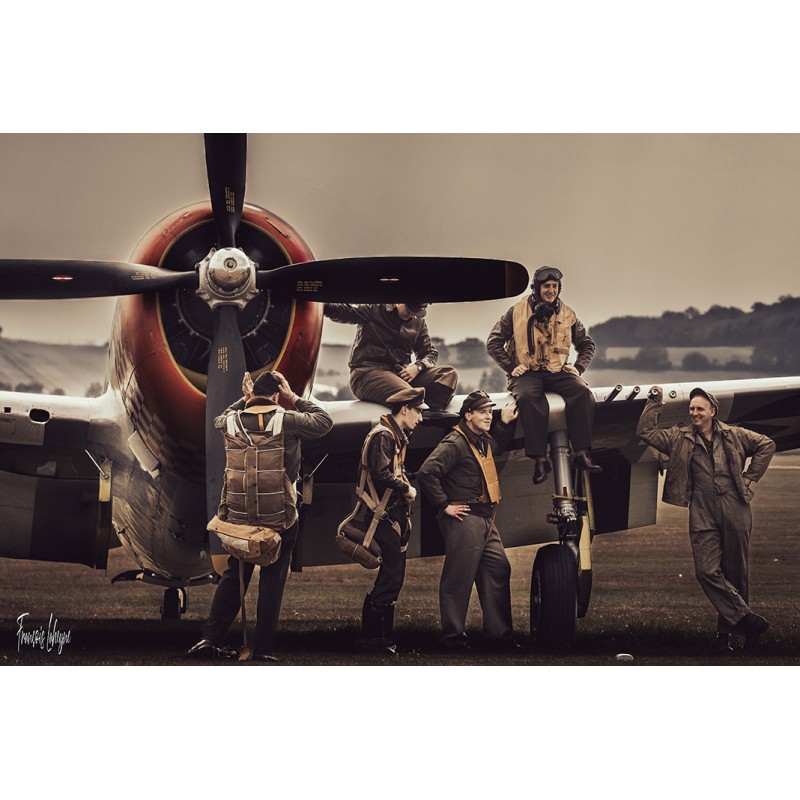 À Duxford, un groupe en tenues d’aviation pose autour d’un Republic P-47 Thunderbolt au sol.