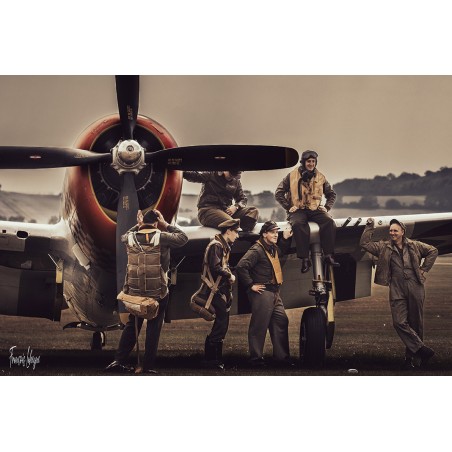 À Duxford, un groupe en tenues d’aviation pose autour d’un Republic P-47 Thunderbolt au sol.